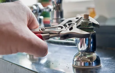 man with crescent wrench fixing old faucet handle